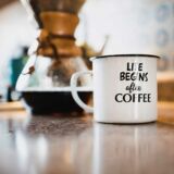 Beschriftete Emaille-Tasse neben einer Kanne mit frisch gebrühtem Kaffee