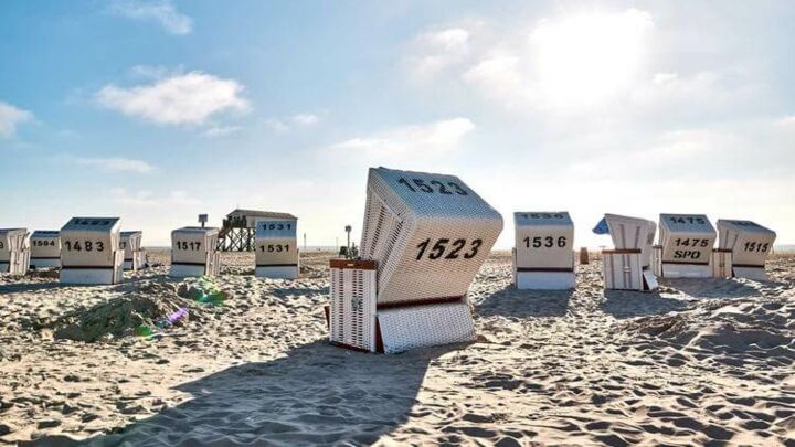 Strandkörbe stehen am Strand bei tiefstehender Sonne