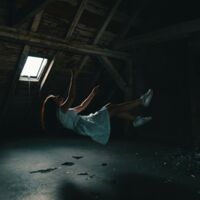 Fall aus dem Glaubenssatz - Momentaufnahme einer fallenden Frau in einem dunklen Raum