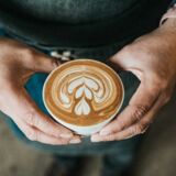 Ein Mann trägt eine Tasse mit Cappuccino